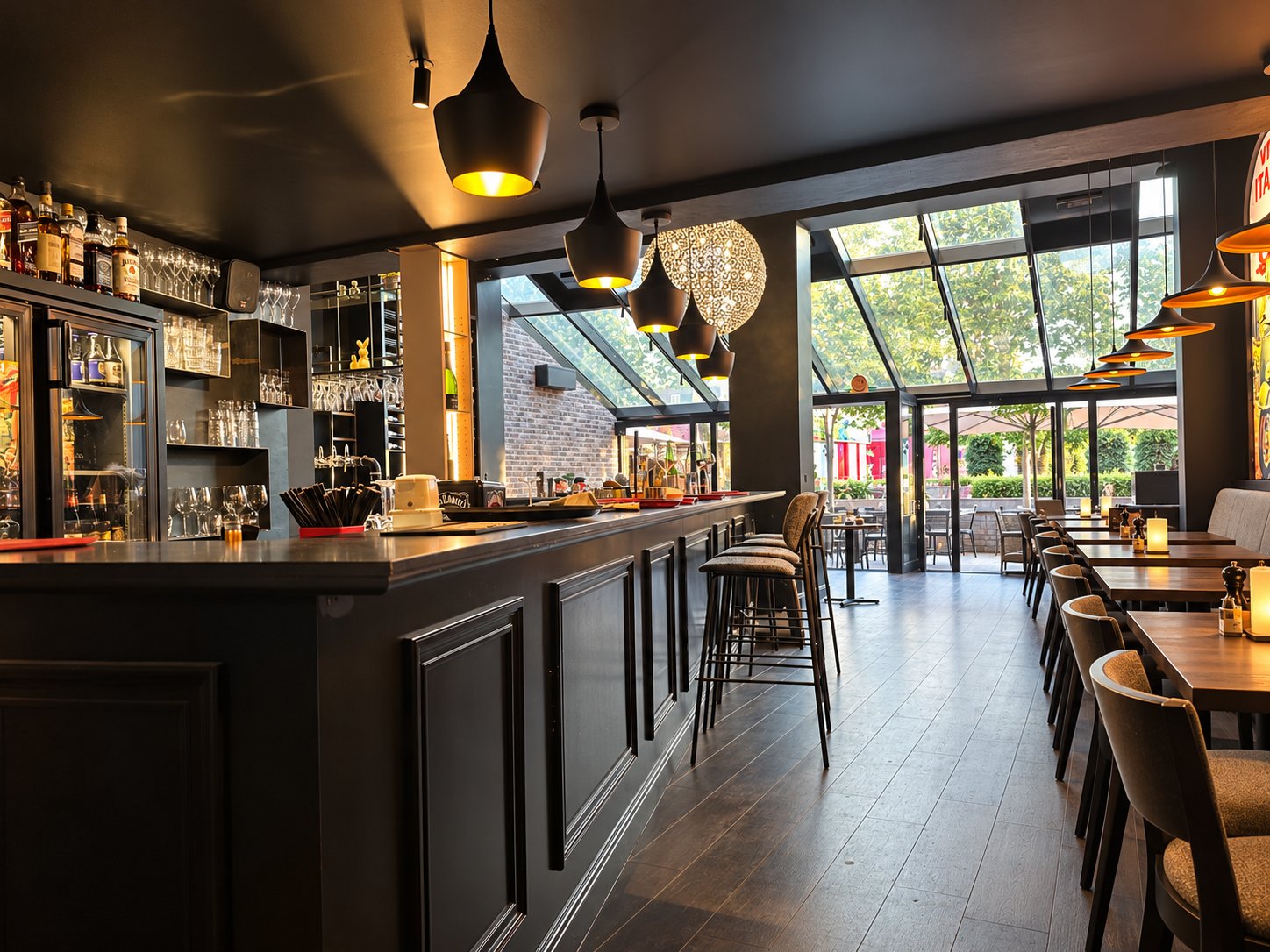 De lange bar van Carlito's Brugge met hanglampen en zicht op de veranda.